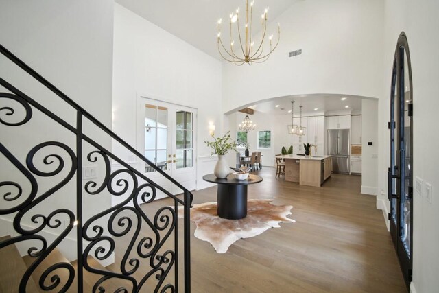 foyer entrance featuring sink, an inviting chandelier, a towering ceiling, wood-type flooring, and french doors