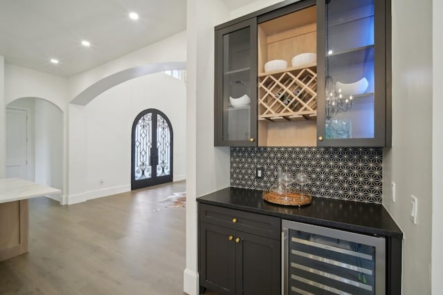 bar with tasteful backsplash, light hardwood / wood-style flooring, beverage cooler, and french doors