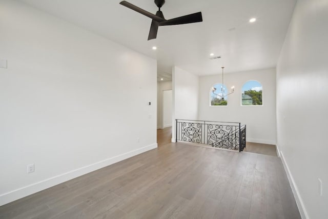 empty room with hardwood / wood-style flooring and ceiling fan with notable chandelier