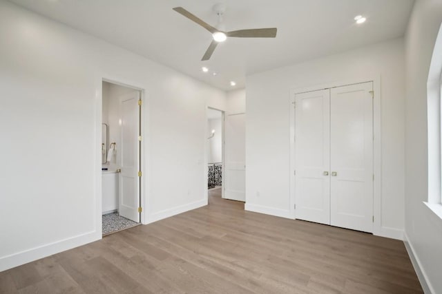 unfurnished bedroom featuring ceiling fan, a closet, ensuite bath, and light hardwood / wood-style flooring