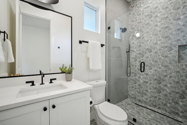 bathroom with vanity, a shower with door, and toilet