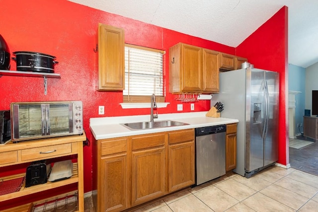 kitchen with sink, light tile patterned floors, a textured ceiling, and appliances with stainless steel finishes