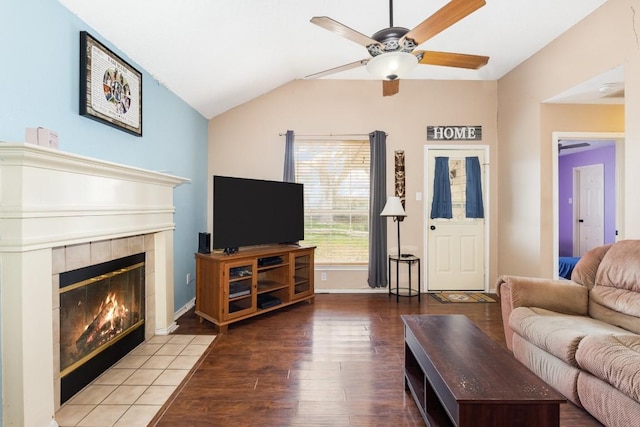 living room featuring hardwood / wood-style floors, vaulted ceiling, a tile fireplace, and ceiling fan