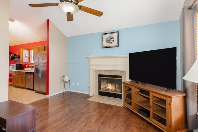 living room with lofted ceiling, a fireplace, light hardwood / wood-style floors, and ceiling fan