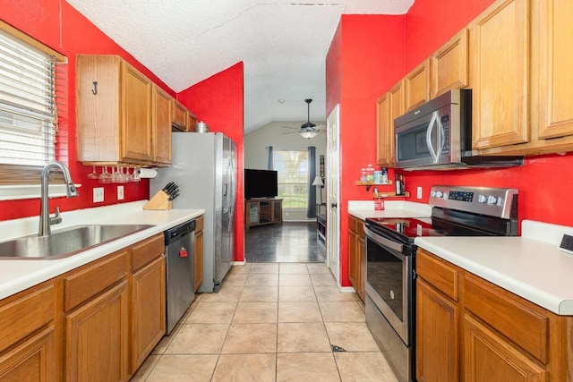 kitchen with sink, vaulted ceiling, light tile patterned floors, ceiling fan, and stainless steel appliances