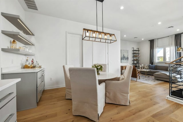 dining area with a notable chandelier, light hardwood / wood-style flooring, and bar area