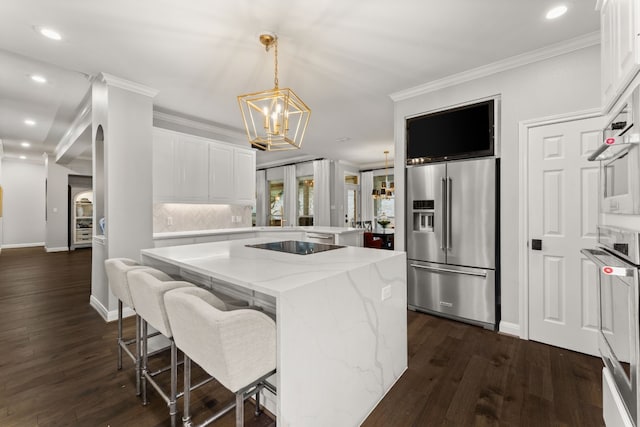 kitchen featuring decorative light fixtures, stainless steel appliances, white cabinets, and a kitchen island