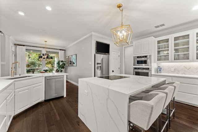 kitchen with white cabinets, appliances with stainless steel finishes, a center island, and a notable chandelier