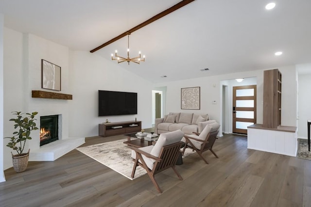 living room featuring lofted ceiling with beams, an inviting chandelier, hardwood / wood-style floors, and a fireplace