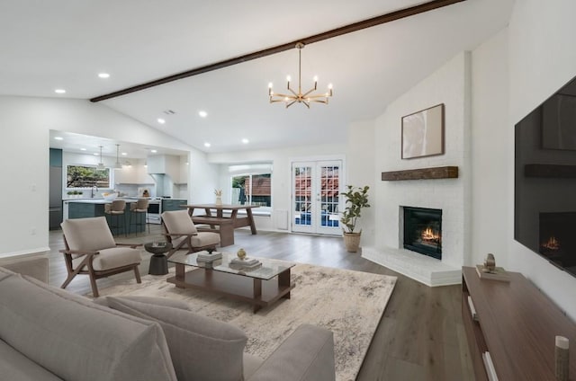 living room with french doors, an inviting chandelier, wood-type flooring, high vaulted ceiling, and a fireplace