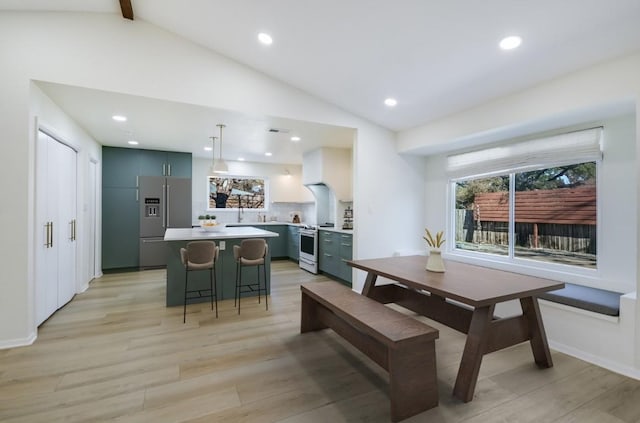 dining room with light hardwood / wood-style flooring and vaulted ceiling