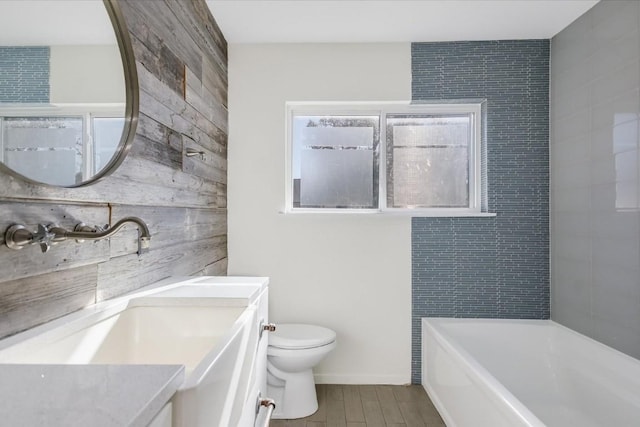 bathroom featuring toilet, wood walls, vanity, a tub, and hardwood / wood-style flooring