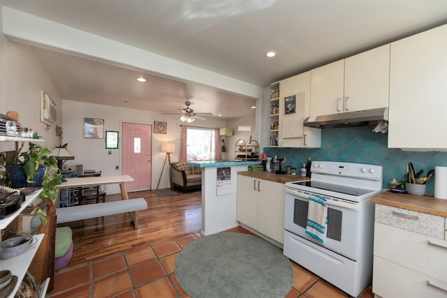 kitchen with wooden counters, dark tile patterned floors, white range with electric cooktop, backsplash, and kitchen peninsula