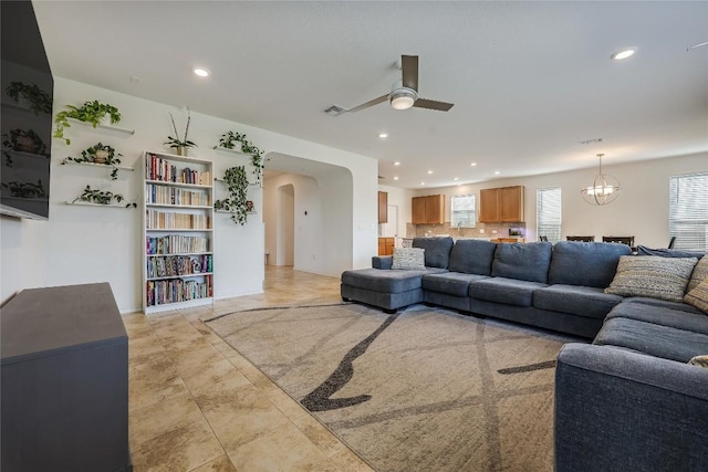 living room with ceiling fan with notable chandelier