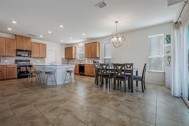 kitchen with a breakfast bar area, an inviting chandelier, hanging light fixtures, a kitchen island, and black appliances