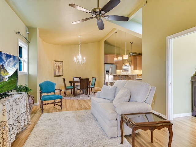 living room featuring lofted ceiling, ceiling fan with notable chandelier, and light wood-type flooring