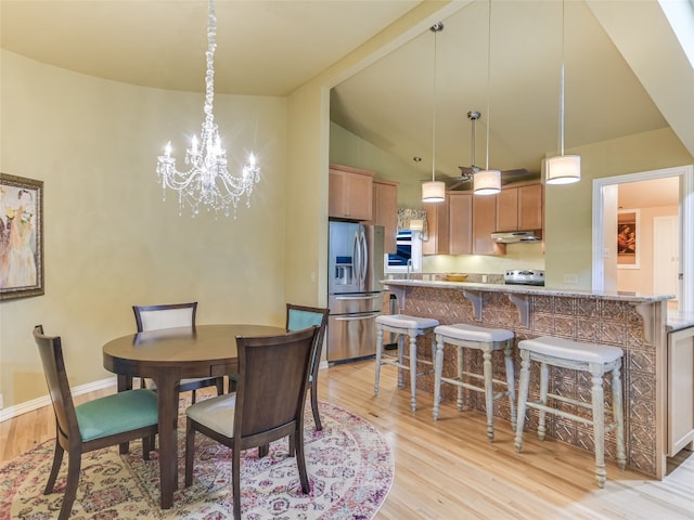 dining space with a notable chandelier, high vaulted ceiling, and light wood-type flooring