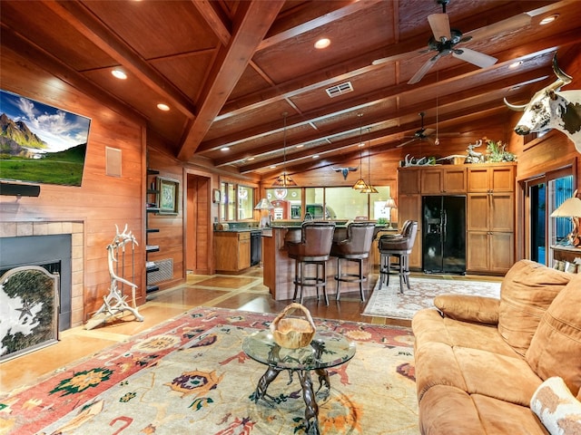 living area featuring vaulted ceiling with beams, a fireplace, visible vents, wood ceiling, and wood walls