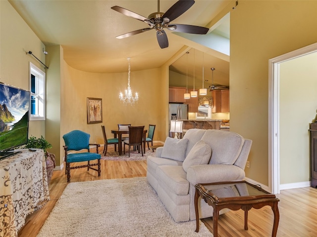 living area with light wood finished floors, baseboards, high vaulted ceiling, and ceiling fan with notable chandelier