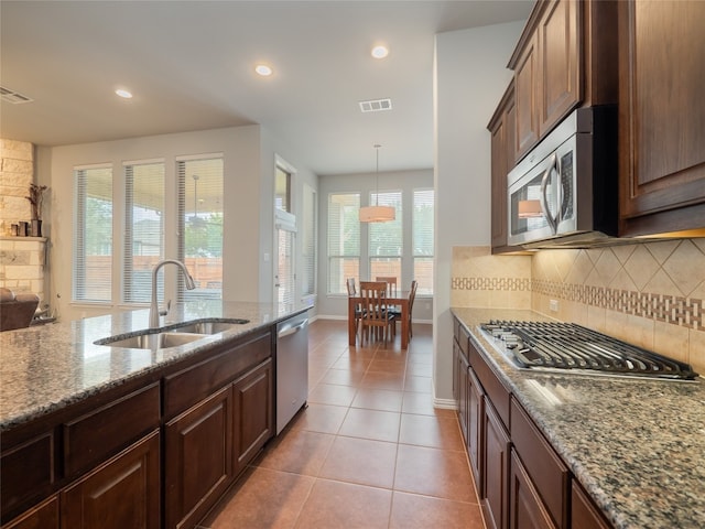 kitchen with sink, light stone counters, light tile patterned flooring, stainless steel appliances, and tasteful backsplash