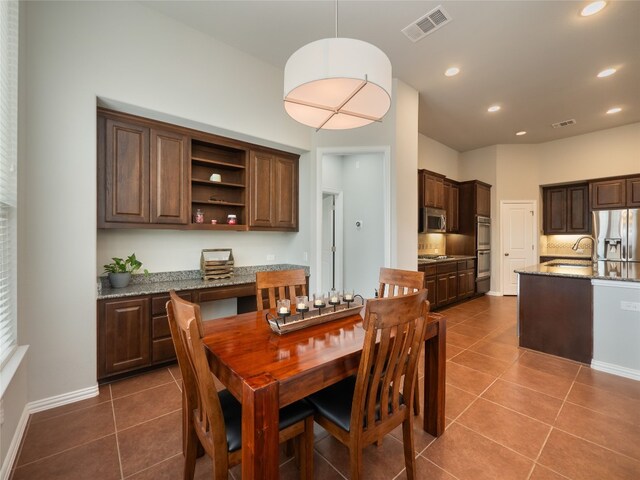 dining space featuring sink and dark tile patterned flooring