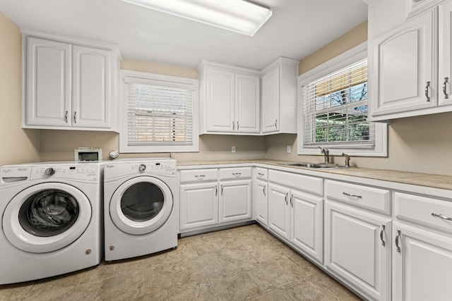 clothes washing area featuring cabinets, sink, and washing machine and clothes dryer