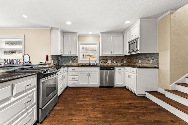 kitchen featuring dark wood-type flooring, stainless steel appliances, dark stone counters, and white cabinets