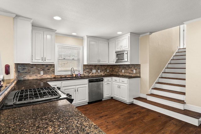 kitchen featuring sink, dark hardwood / wood-style floors, white cabinets, stainless steel appliances, and backsplash