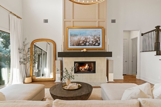 living room featuring a towering ceiling, a fireplace, and wood-type flooring