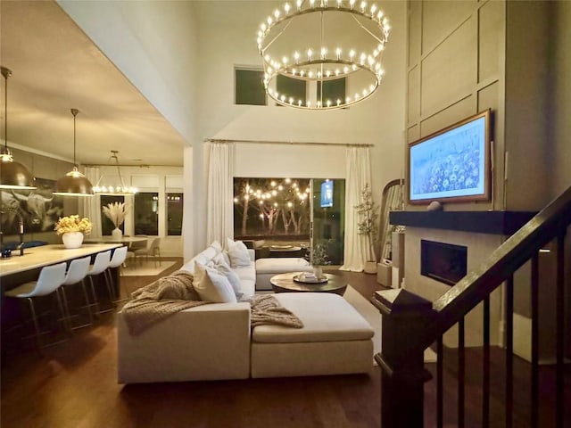 living room with an inviting chandelier, a towering ceiling, and dark hardwood / wood-style floors