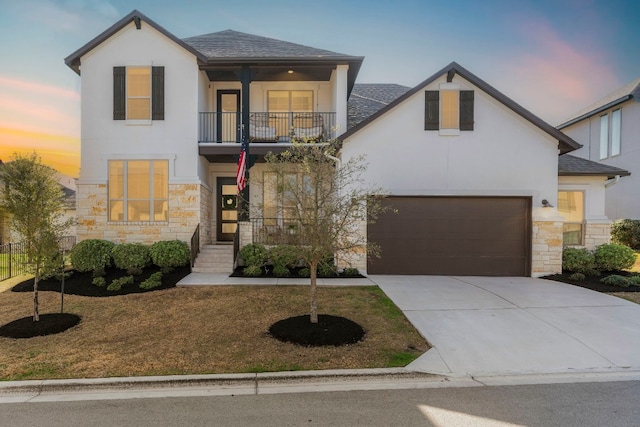 view of front of property featuring stone siding, driveway, a balcony, and stucco siding