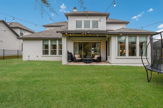 rear view of house featuring a yard, a trampoline, fence, and a patio