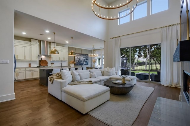 living room with a wealth of natural light, dark wood finished floors, a notable chandelier, and a lit fireplace