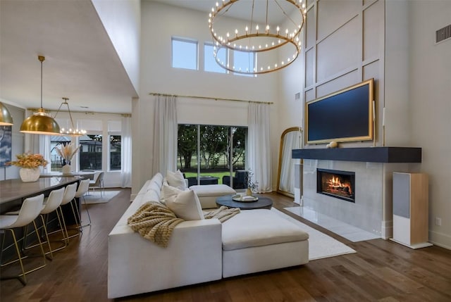 living area with dark wood finished floors, a fireplace, a notable chandelier, and a high ceiling