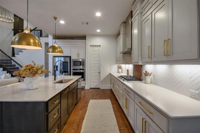 kitchen with appliances with stainless steel finishes, light countertops, a center island with sink, and visible vents