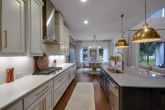 kitchen with a kitchen island with sink, a sink, light countertops, appliances with stainless steel finishes, and decorative light fixtures