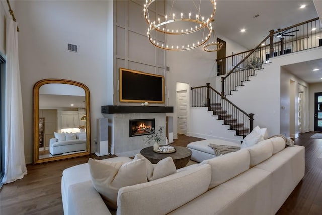 living area with dark wood-style flooring, visible vents, a tiled fireplace, and stairs