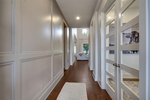 corridor with recessed lighting, baseboards, dark wood finished floors, and a decorative wall