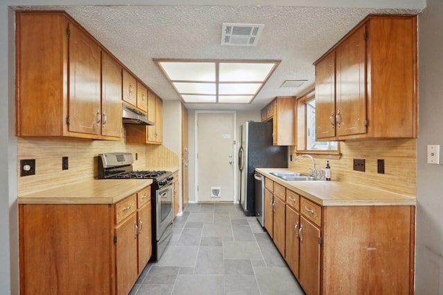 kitchen with stainless steel appliances, sink, backsplash, and a textured ceiling