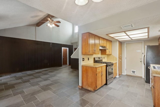 kitchen with vaulted ceiling with beams, a textured ceiling, ceiling fan, stainless steel appliances, and decorative backsplash