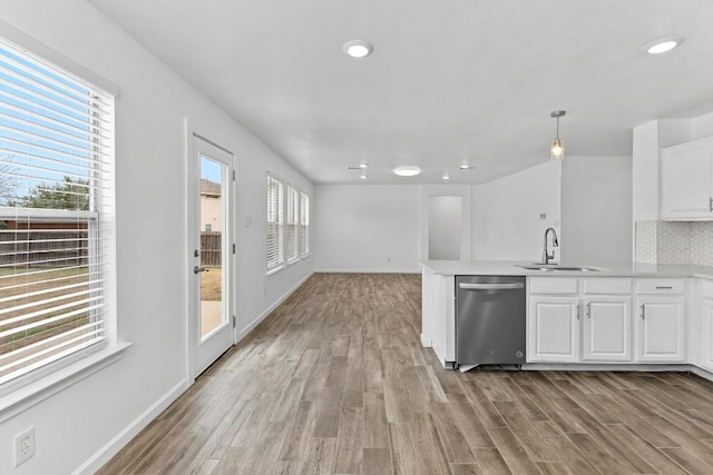 kitchen featuring white cabinetry, pendant lighting, stainless steel dishwasher, and light hardwood / wood-style floors