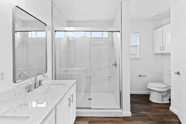 bathroom with vanity, hardwood / wood-style floors, a shower with door, and toilet