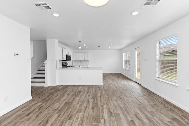 unfurnished living room featuring sink and light hardwood / wood-style flooring