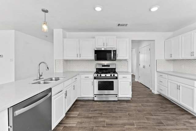 kitchen with sink, white cabinetry, hanging light fixtures, stainless steel appliances, and tasteful backsplash