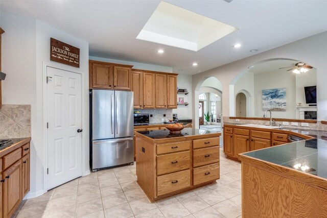 kitchen with stainless steel refrigerator, sink, backsplash, a center island, and light tile patterned floors