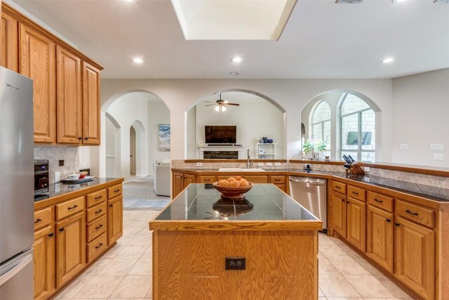 kitchen featuring decorative backsplash, a center island, tile counters, light tile patterned floors, and stainless steel appliances