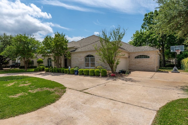 view of front of home featuring an attached garage, driveway, a front lawn, and stone siding