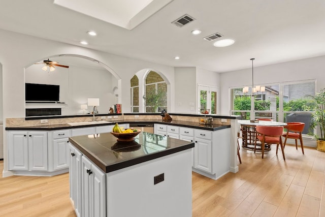 kitchen with a peninsula, dark countertops, visible vents, and a center island