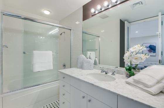 full bath featuring visible vents, combined bath / shower with glass door, and vanity