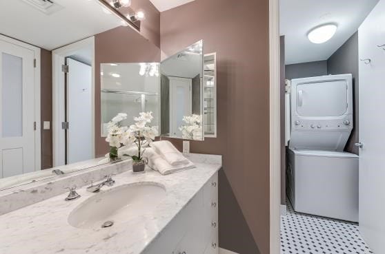 bathroom with stacked washer and clothes dryer, visible vents, and vanity